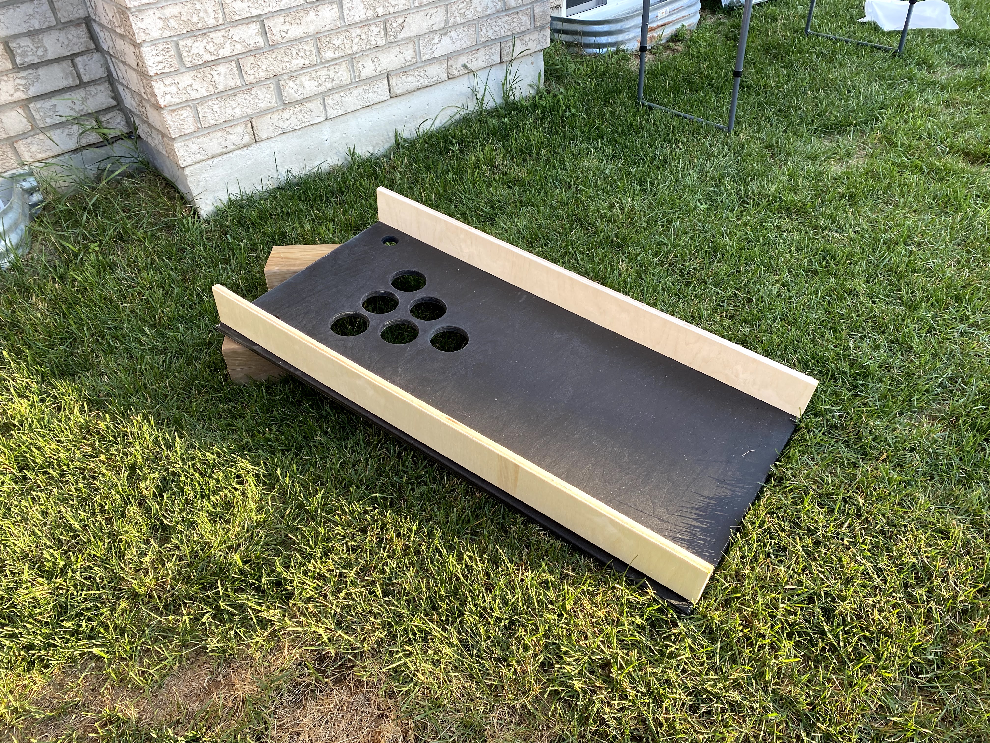 cornhole board in backyard on grass